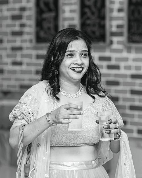 Grayscale Photo of Smiling Woman Holding Glasses of Water