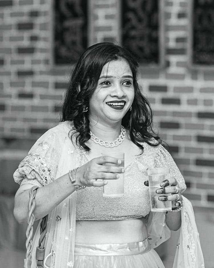 Grayscale Photo Of Smiling Woman Holding Glasses Of Water