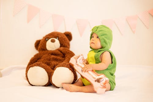 Infant in a Costume Sitting by a Teddy Bear