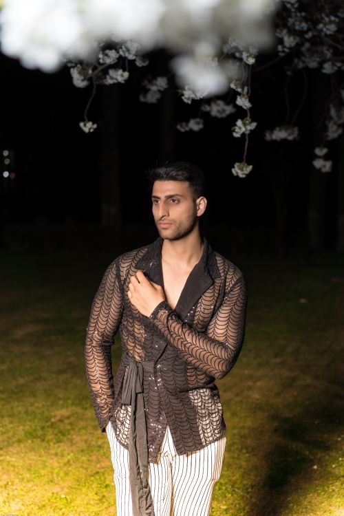 Free Stylish male model posed under cherry blossoms during a nighttime fashion shoot. Stock Photo