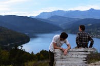 两个朋友在风景秀丽的山湖边放松，拥抱宁静的自然景观