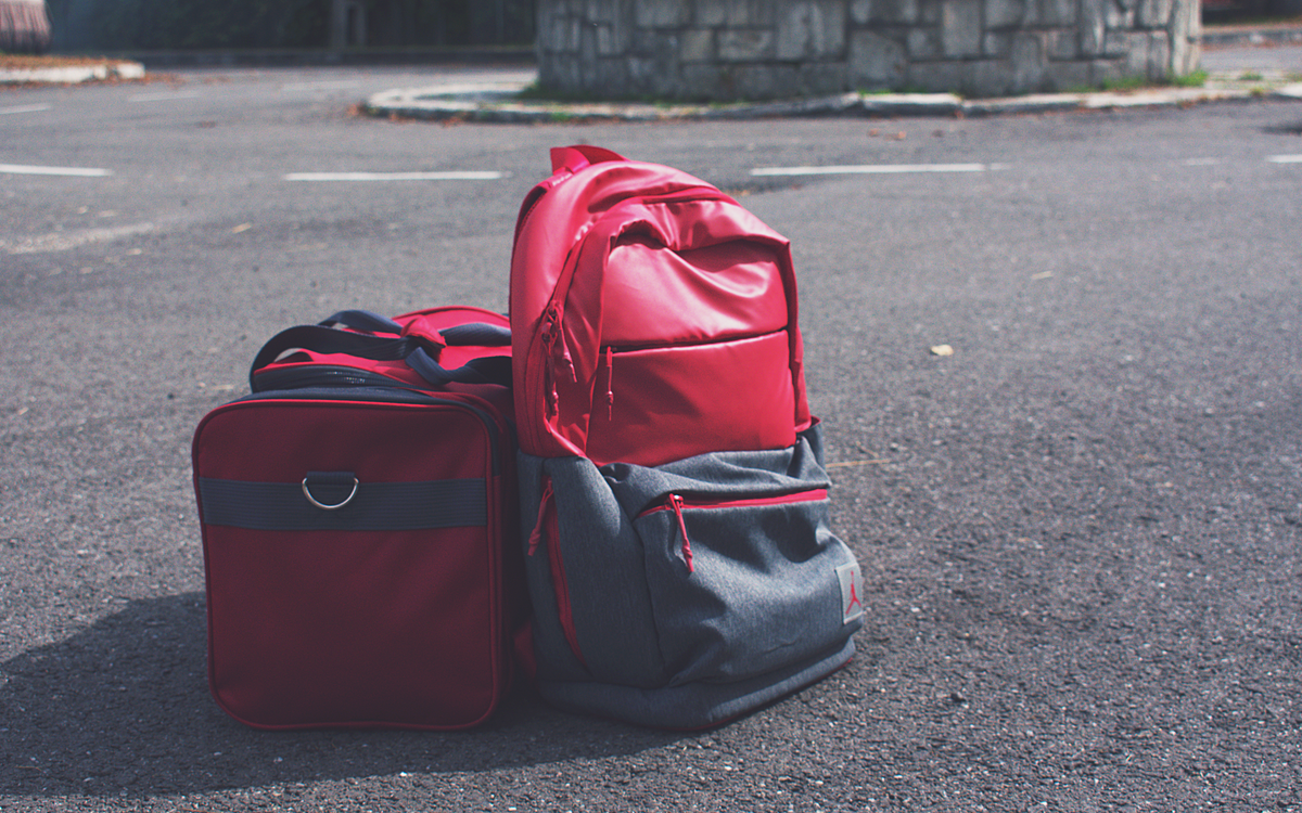 Red backpack and matching bag on asphalt, perfect for travel themes.