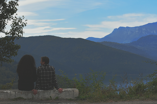 Free A couple enjoying the serene view of a mountain lake, surrounded by nature. Stock Photo