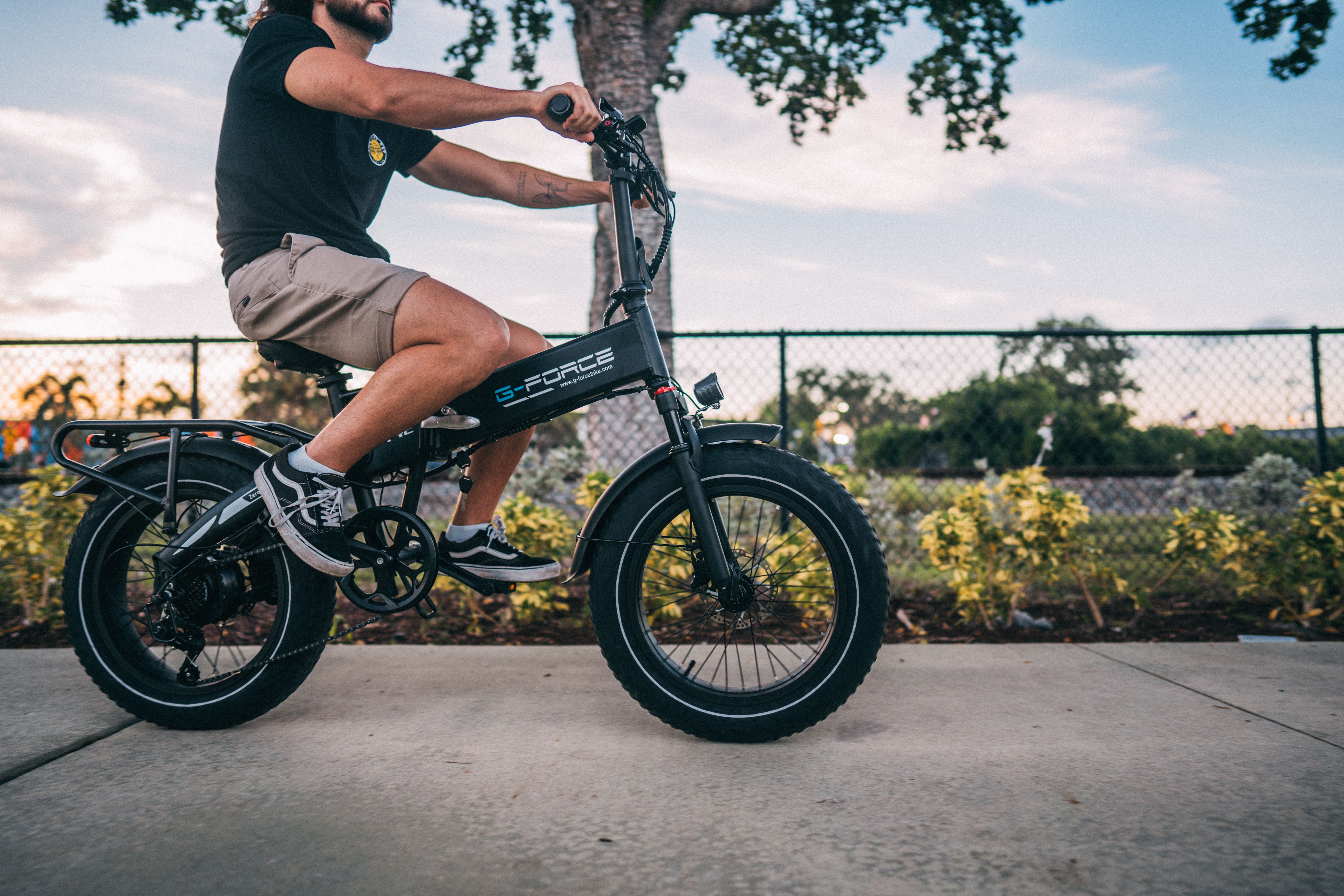 Man riding an electric bike down a sunny city street.