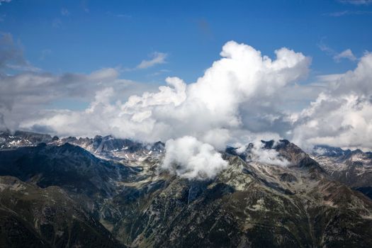 A breathtaking aerial view of a rugged mountain range with clouds over the peaks.