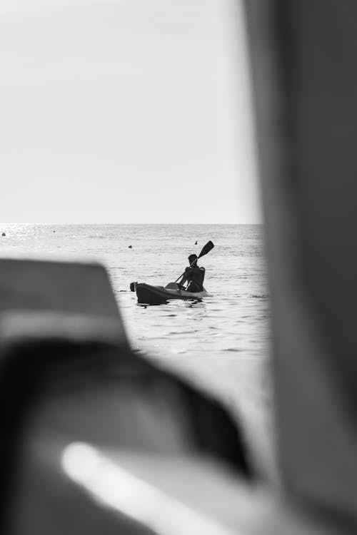 Grayscale Photo of Person Paddling a Canoe