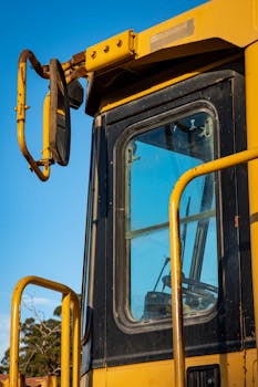 Detail of an industrial construction vehicle with cab window and rearview mirror.