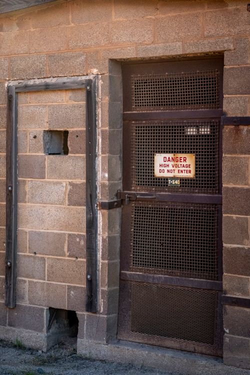 Free Grungy industrial door with warning sign for high voltage. Perfect for conveying danger or industrial themes. Stock Photo