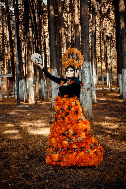 Woman in a Black and Orange Floral Dress Holding a Skull