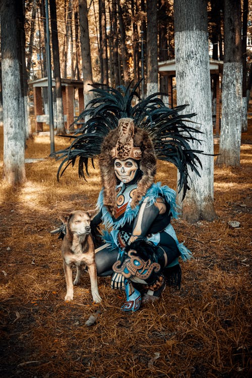 Person in Dia de Muertos Costume Posing with Dog in Forest