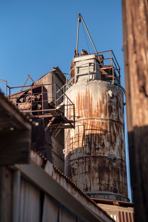 Free A weathered, rusty silo in an industrial outdoor setting under clear sky, displaying decay. Stock Photo
