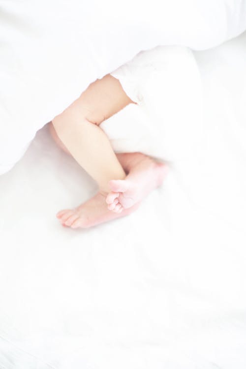 Free Baby Wearing a Diaper Lying on a White Bed Stock Photo