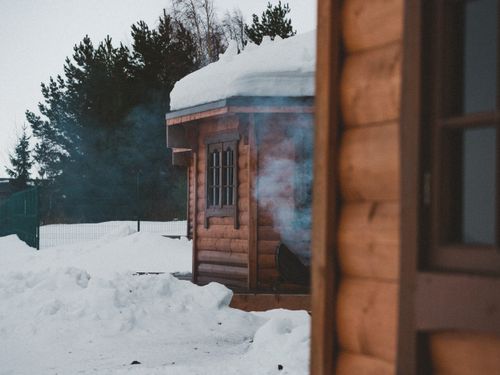 Free A rustic log cabin surrounded by snow in a serene winter forest setting. Stock Photo