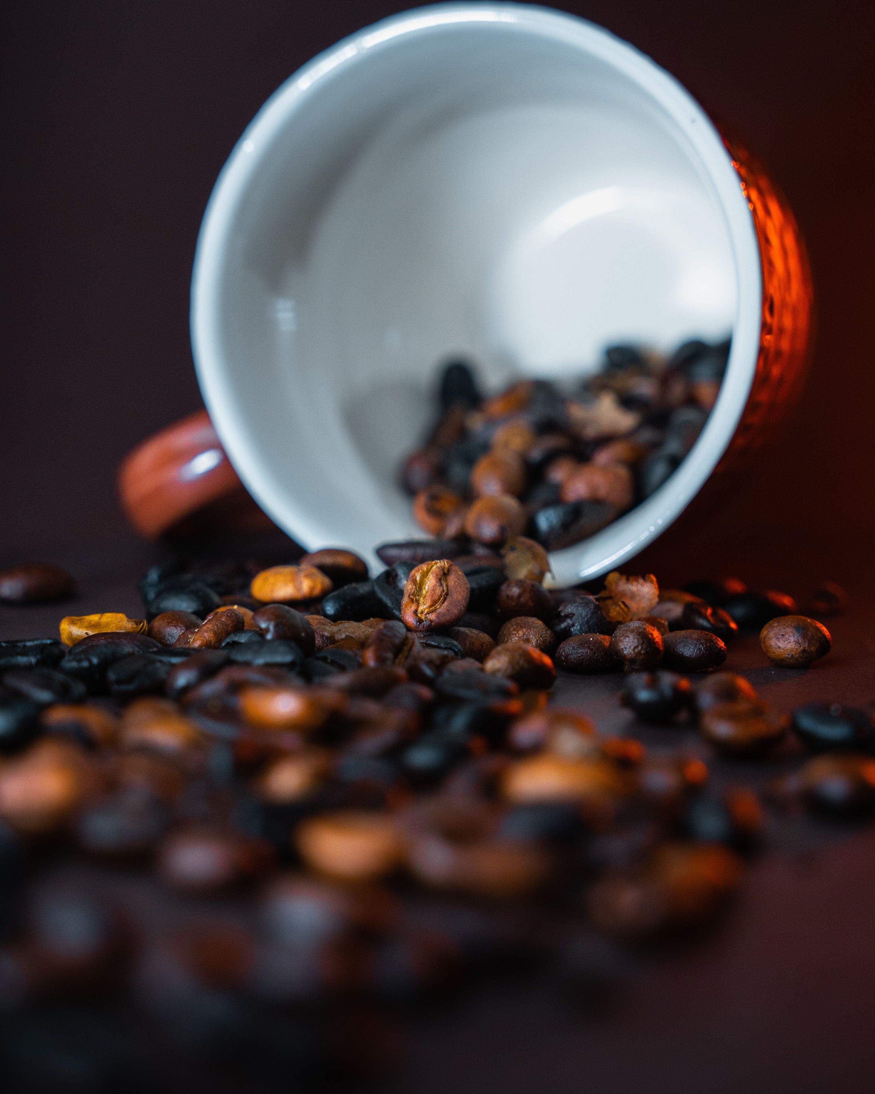 A close-up of coffee beans spilling from a cup with a warm, selective focus highlighting rich textures.