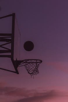 Silhouette of a basketball hoop and ball during twilight over a purple sky in Bhubaneswar, India.