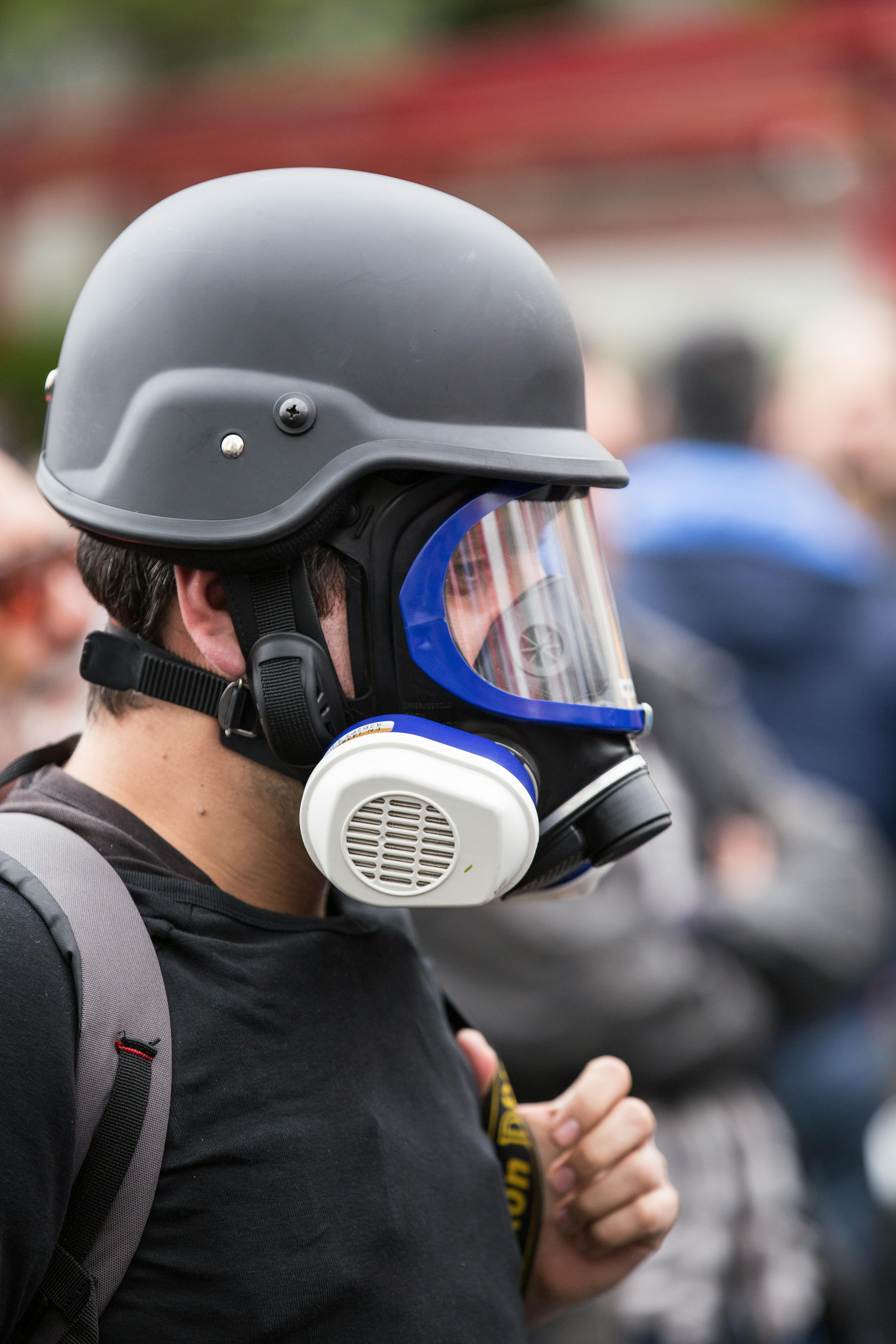 黒い防毒マスクと保護用ヘルメットをかぶった男 無料の写真素材