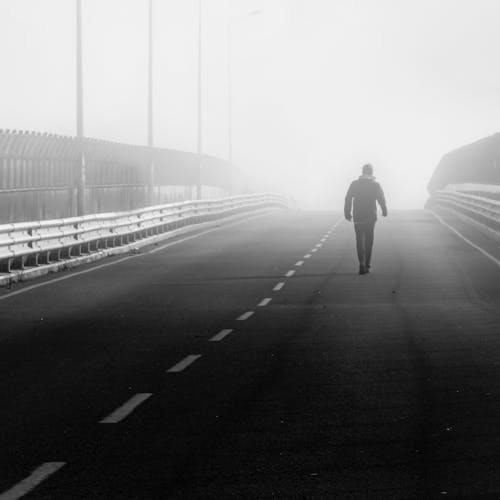 Man Walking on an Empty Highway in Fog 