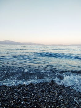 希腊基亚托卵石海滩在日出时呈现出一片宁静景色，大海平静无波