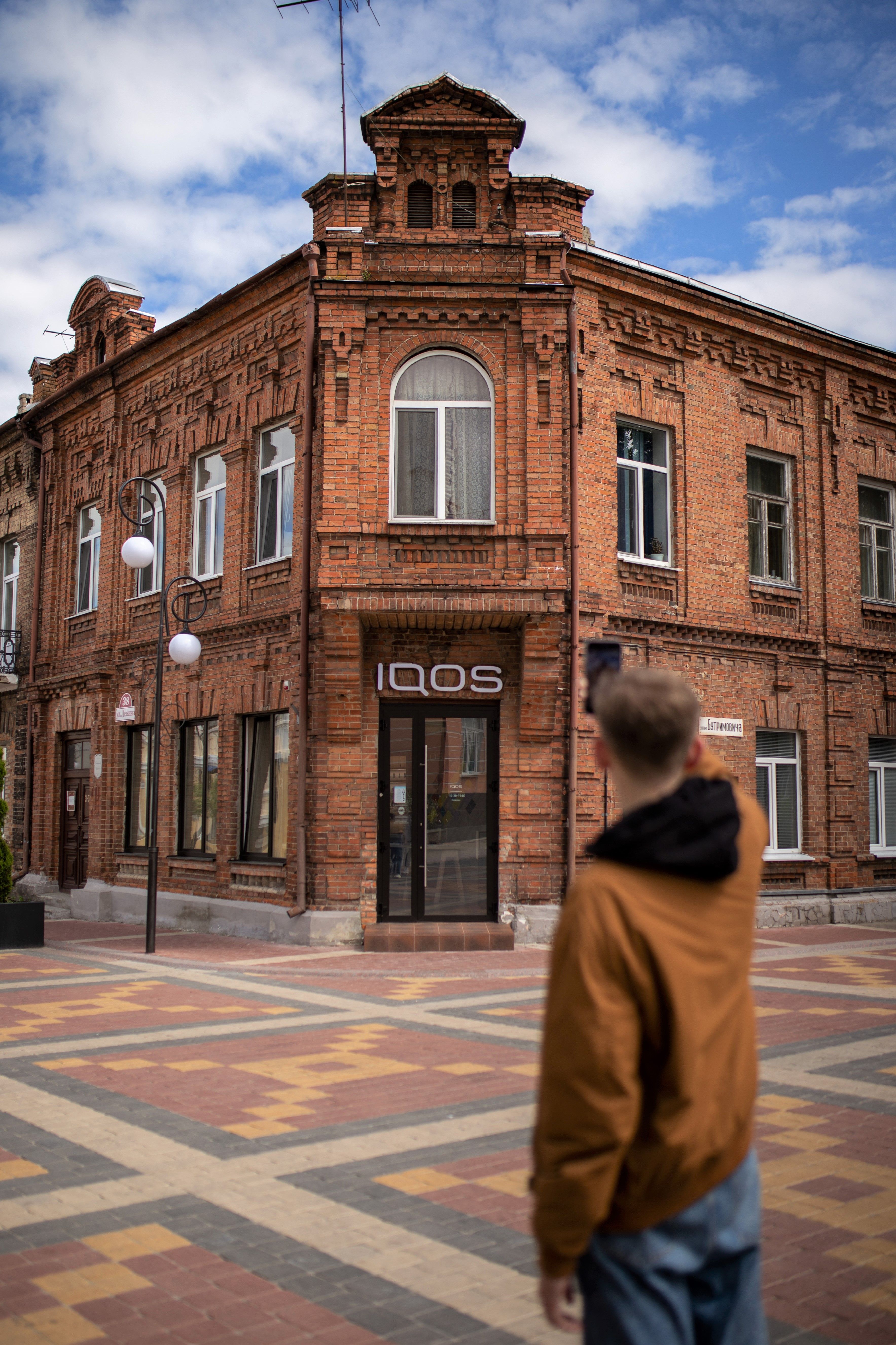 A man photographs a historic brick building in Pinsk with a classic facade.