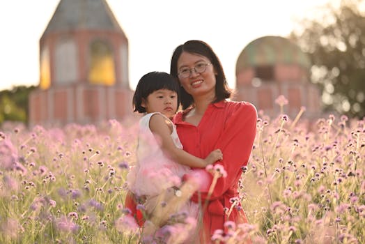 A joyful portrait of a mother and child surrounded by vivid flowers on a sunny day.