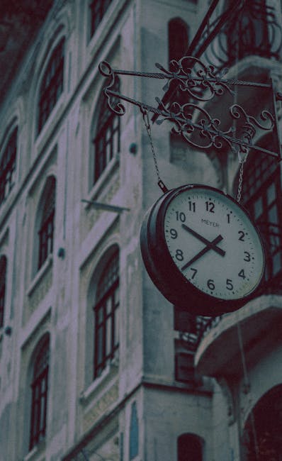 Vintage analog clock hanging on a historic building facade,