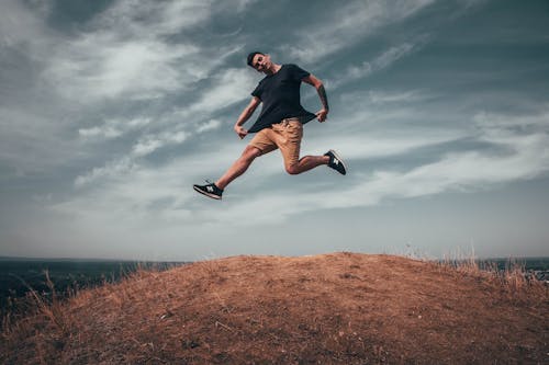 Free Man Jumping on Brown Soil Stock Photo