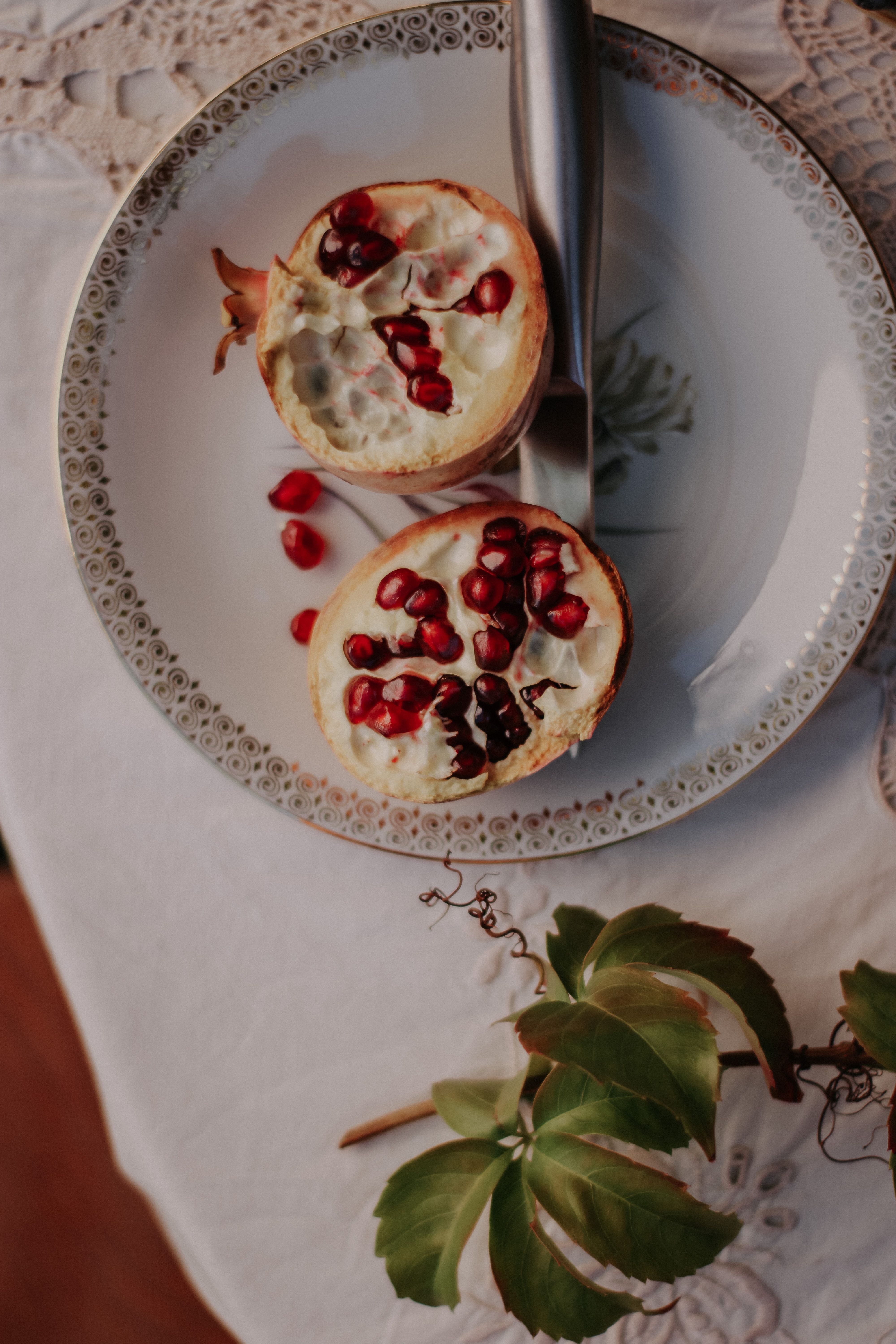 A beautifully arranged cut pomegranate on a decorative plate, showcasing vibrant red seeds.