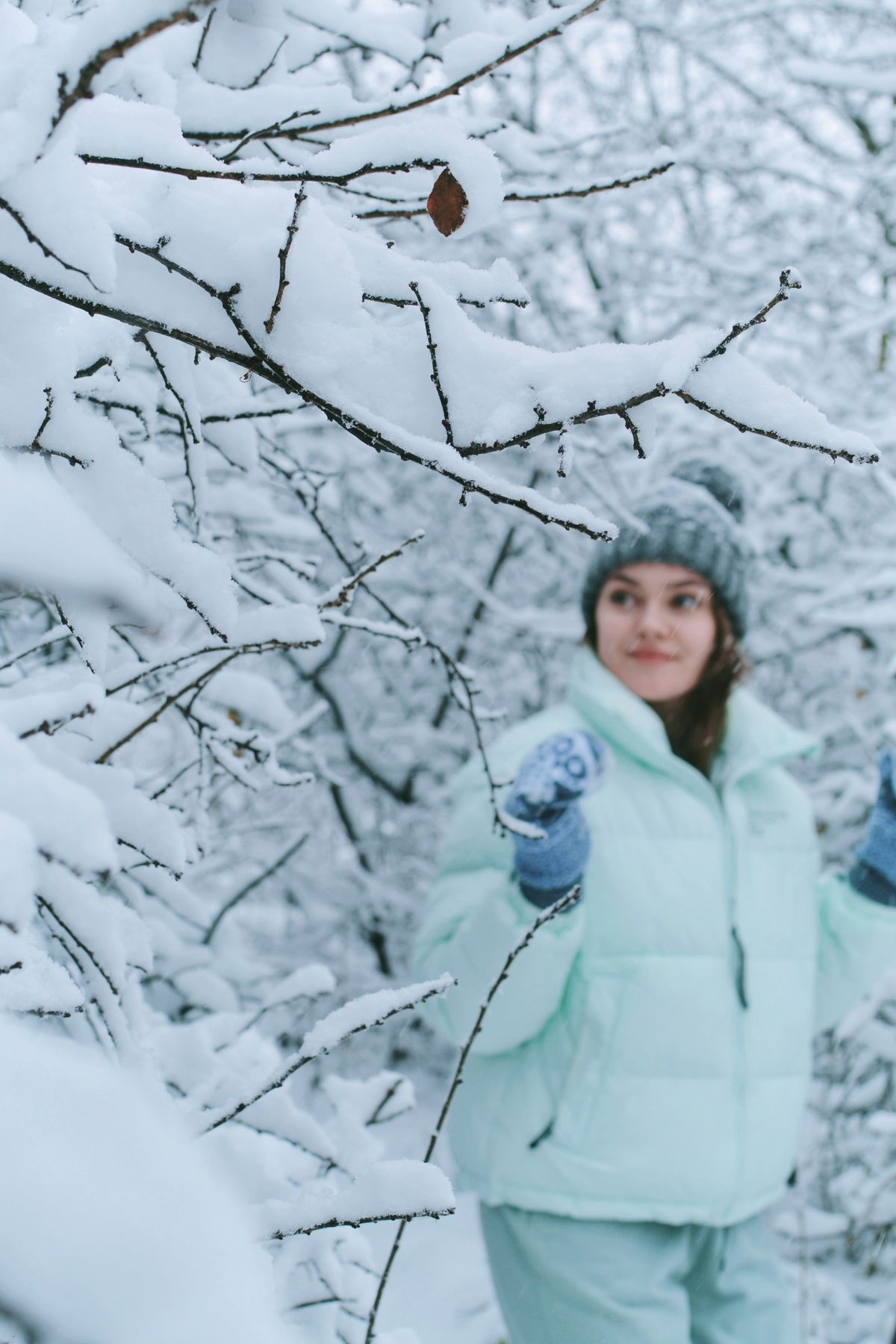 Woman in winter clothing standing in a snowy forest