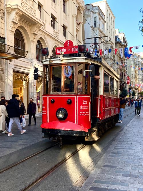 Free Vintage red tram on historic Istiklal Street in Istanbul with vibrant city life around. Stock Photo