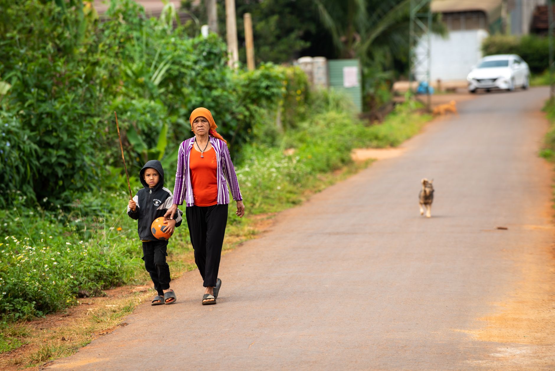 A woman and her child walk along a rural road in Đắk Lắk, Vietnam, capturing everyday family life.
