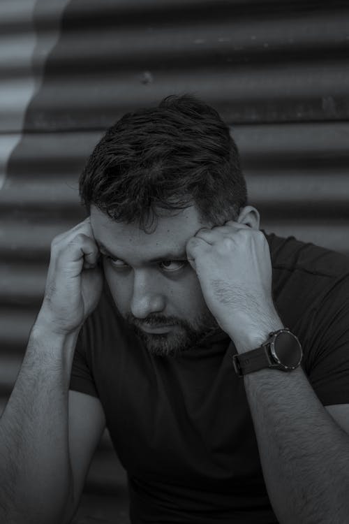 A Grayscale Photo of a Man with His Hands on His Head