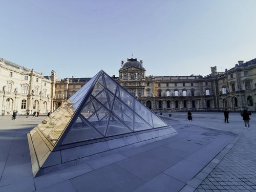 Free View of the iconic glass pyramid at the Louvre Museum in Paris with a clear blue sky. Stock Photo