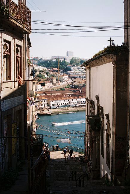 A picturesque view of Porto's historic alley and buildings leading down to the Douro River.