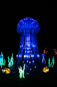 Vibrant illuminated jellyfish art installation glowing against a dark night sky.