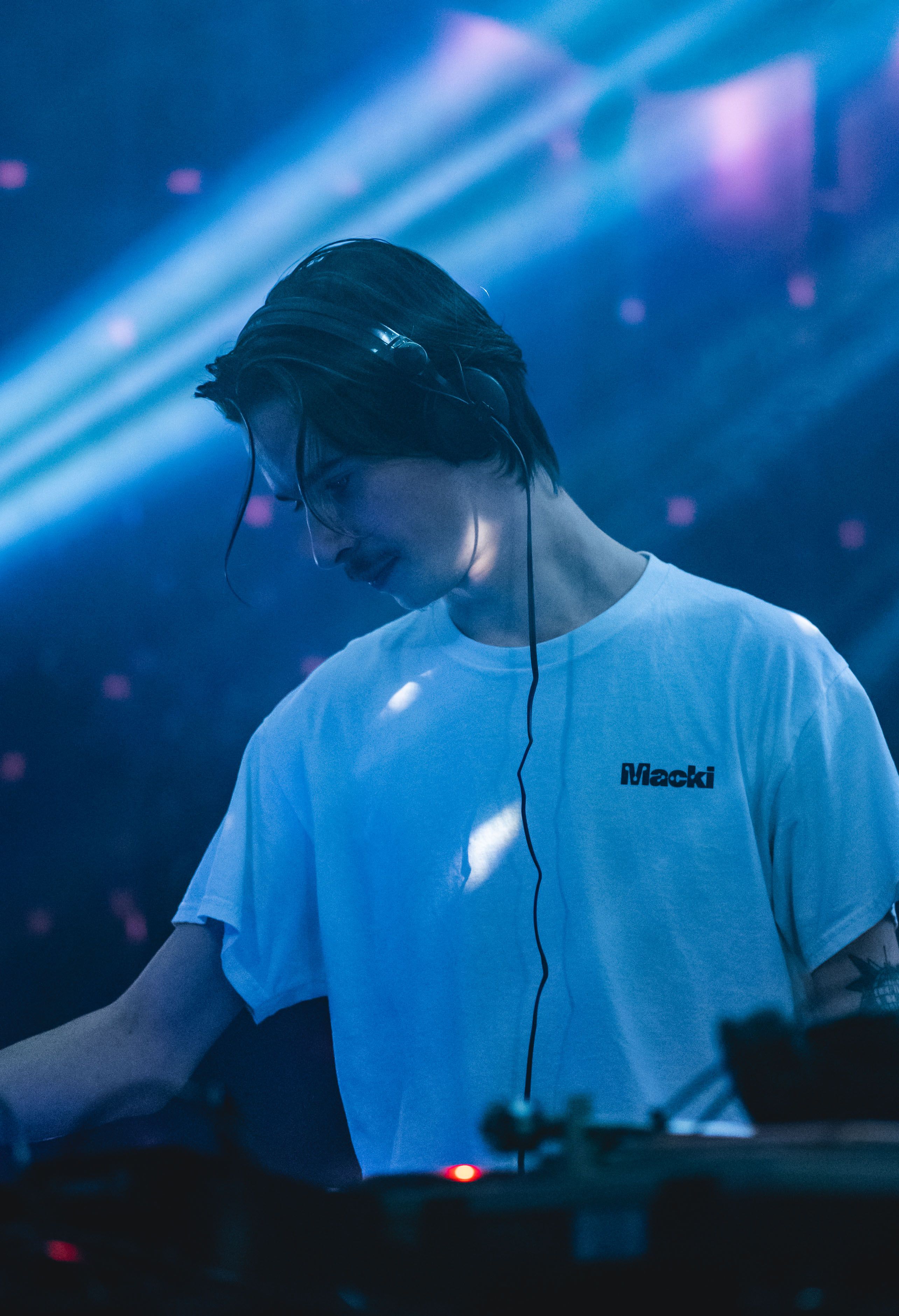 A DJ wearing headphones playing music in a vibrant club setting in Angers, France.