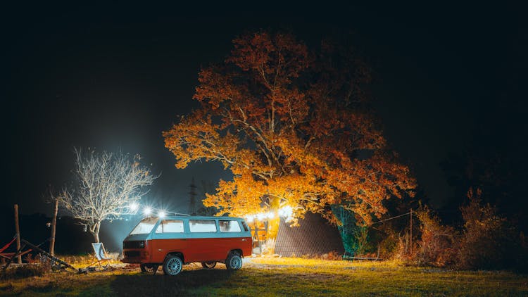 A Camper Van Parked On Green Grass Field At Night