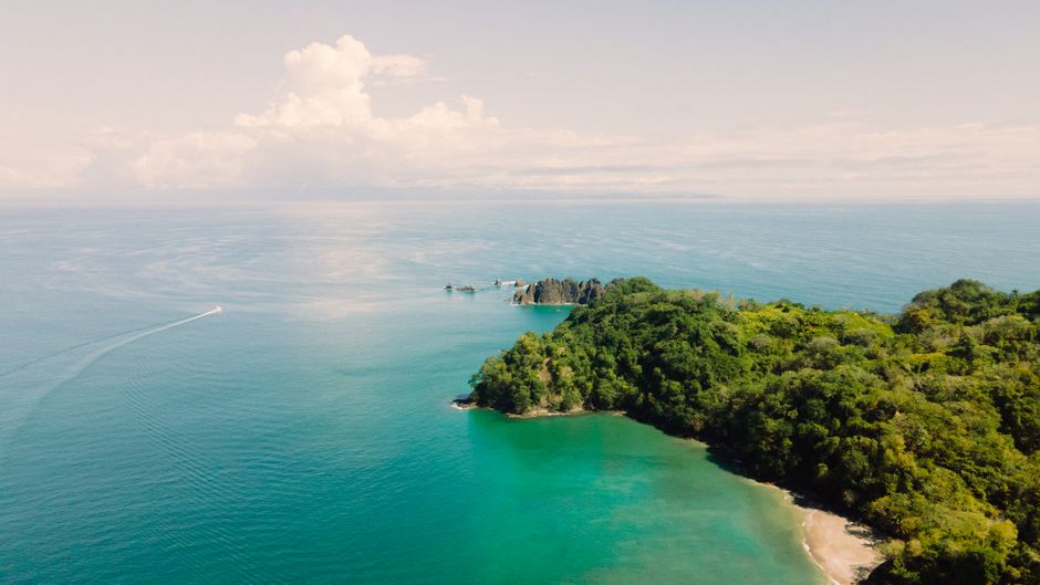 Stunning aerial shot of a tropical island surrounded by clear blue sea and lush green landscape.