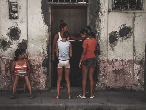 Free A group of people interacting in an urban setting with worn-out walls and a doorway. Stock Photo