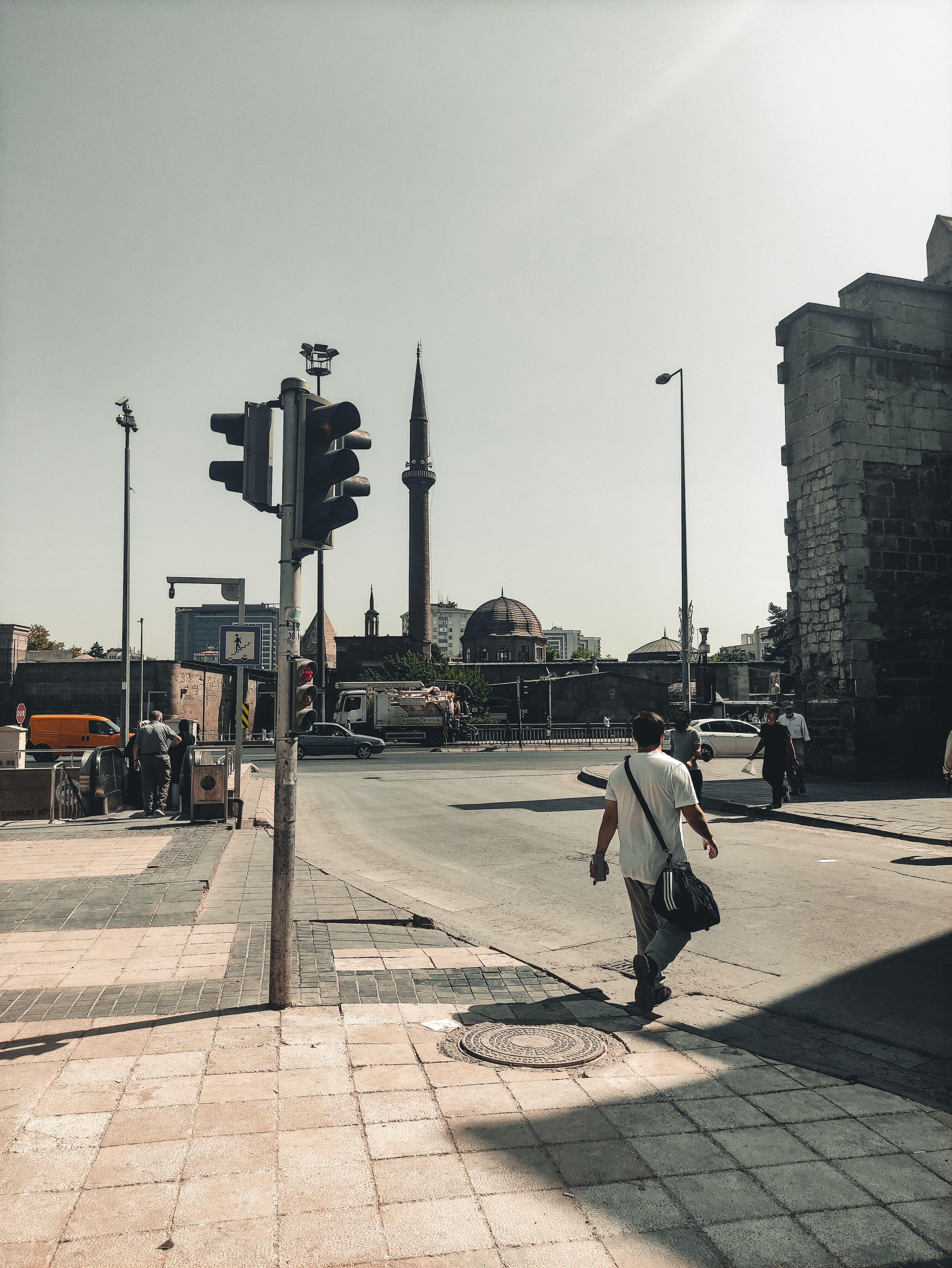 A bustling Kayseri street with people walking and a mosque in the background.