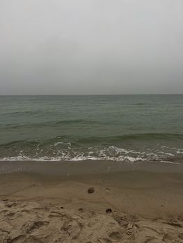 Calm seas and sandy beach under overcast skies, capturing tranquility of nature.