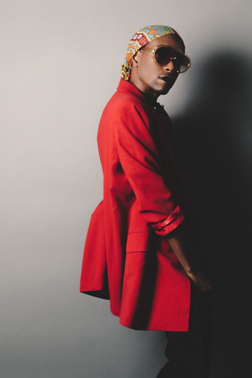 Free Fashionable portrait featuring a person in a red blazer, bandana, and sunglasses against a gray background. Stock Photo