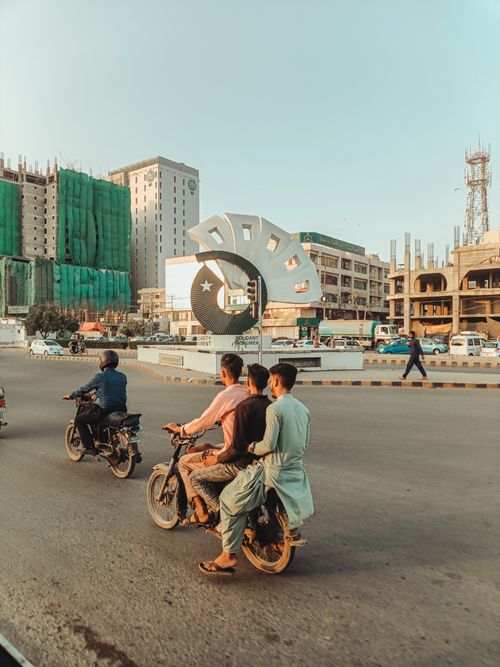 Free Group of motorcyclists riding through a busy urban street with a prominent landmark in view. Stock Photo