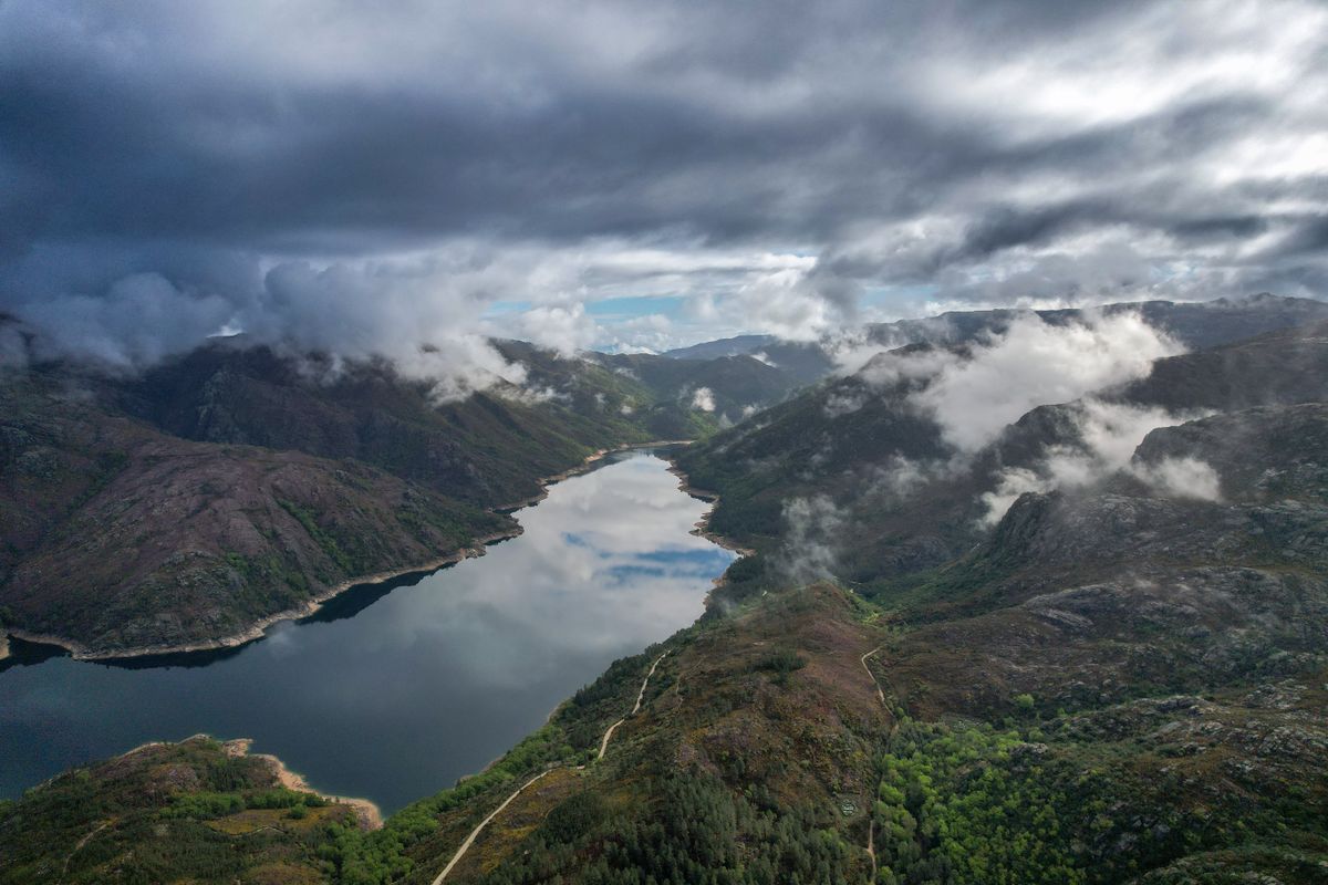 A lake among green mountains under white clouds