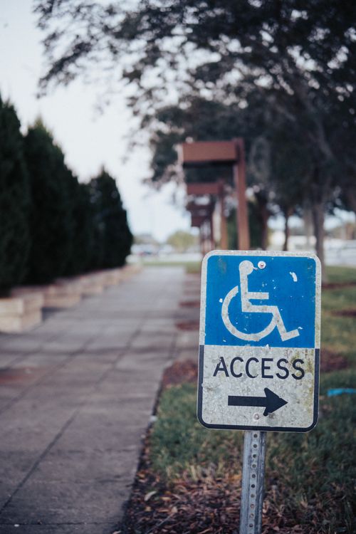 Free Image of a wheelchair access sign on a paved pathway outdoors, suggesting accessibility. Stock Photo