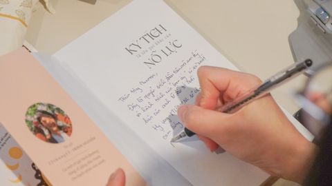 Woman writing a letter in a cozy indoor setting with personal stationery.