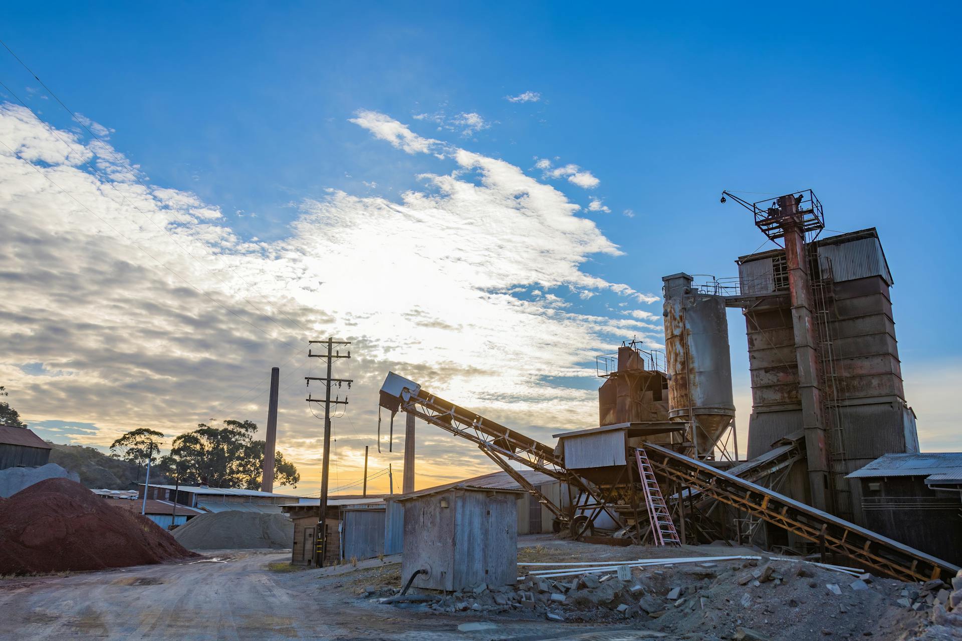 A factory with rusty structures set against a stunning sunrise in an industrial landscape.