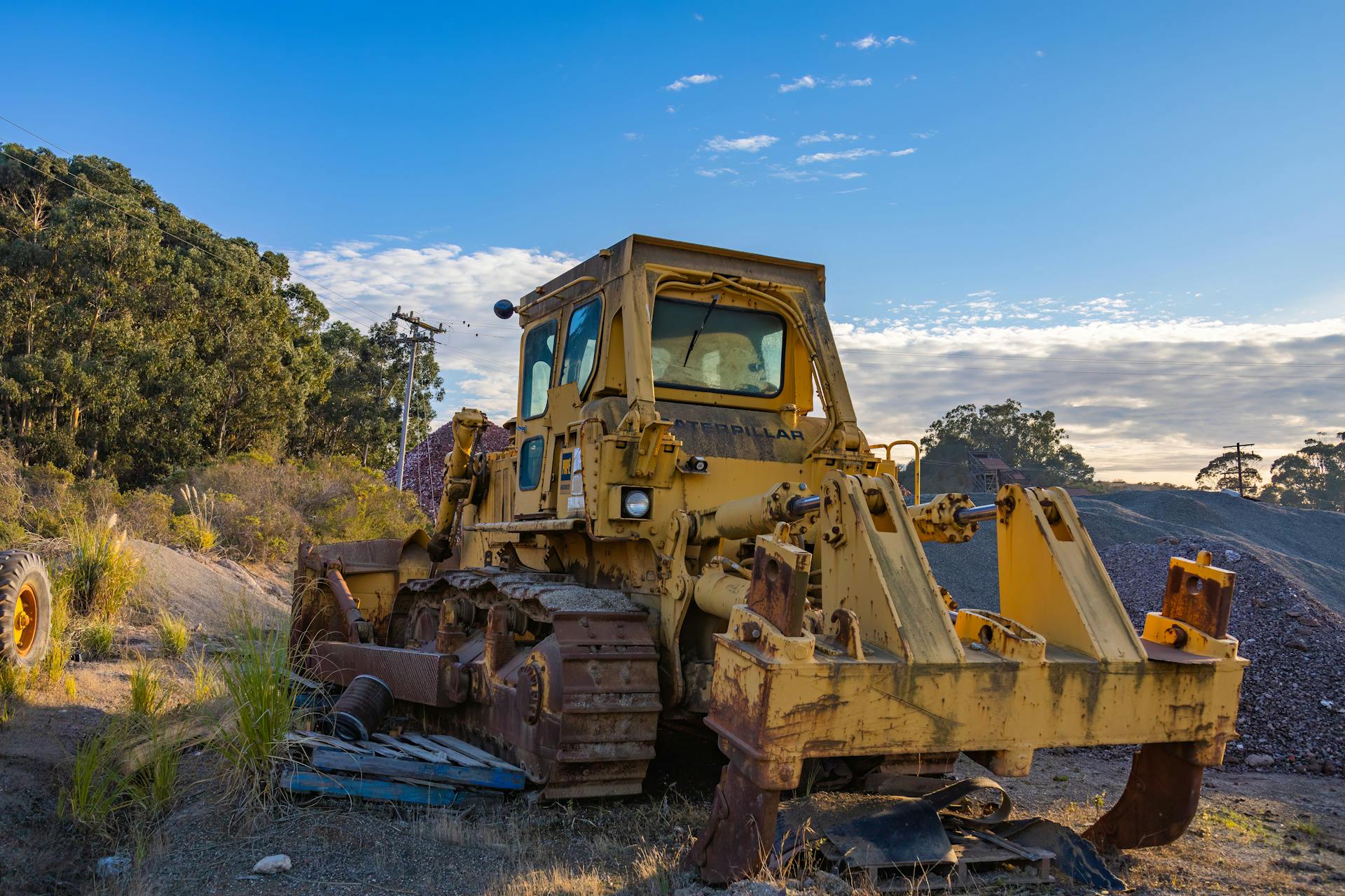 Bulldozer on a construction site with piles of earth, set against a clear blue sky.