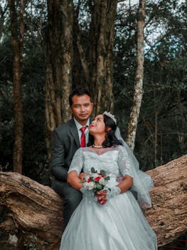 Bride and groom in elegant attire enjoying a serene moment in a forest setting.