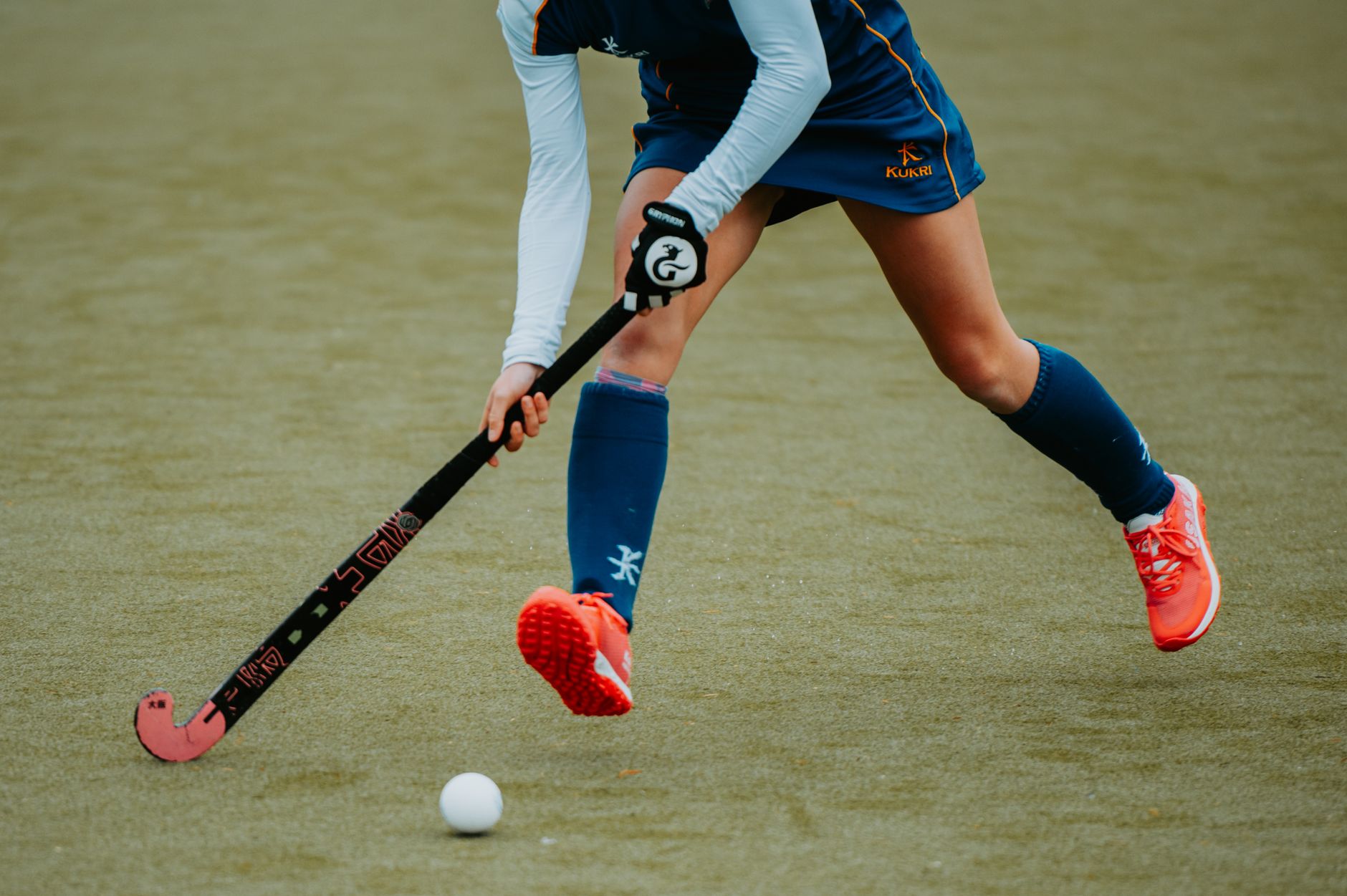 Action shot of an athlete playing field hockey on a turf field.