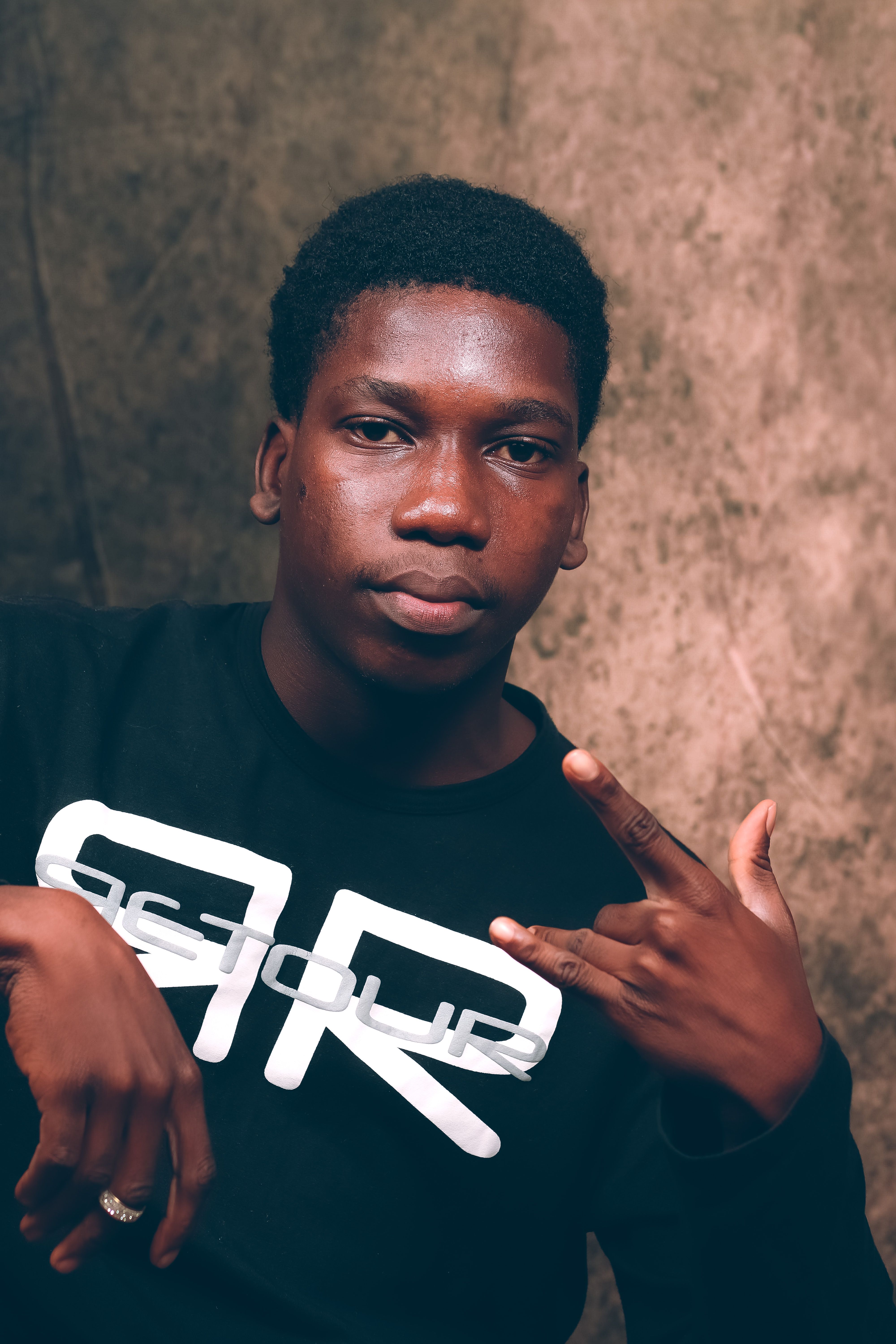 Portrait of a young man indoors with confident expression and hand gesture.